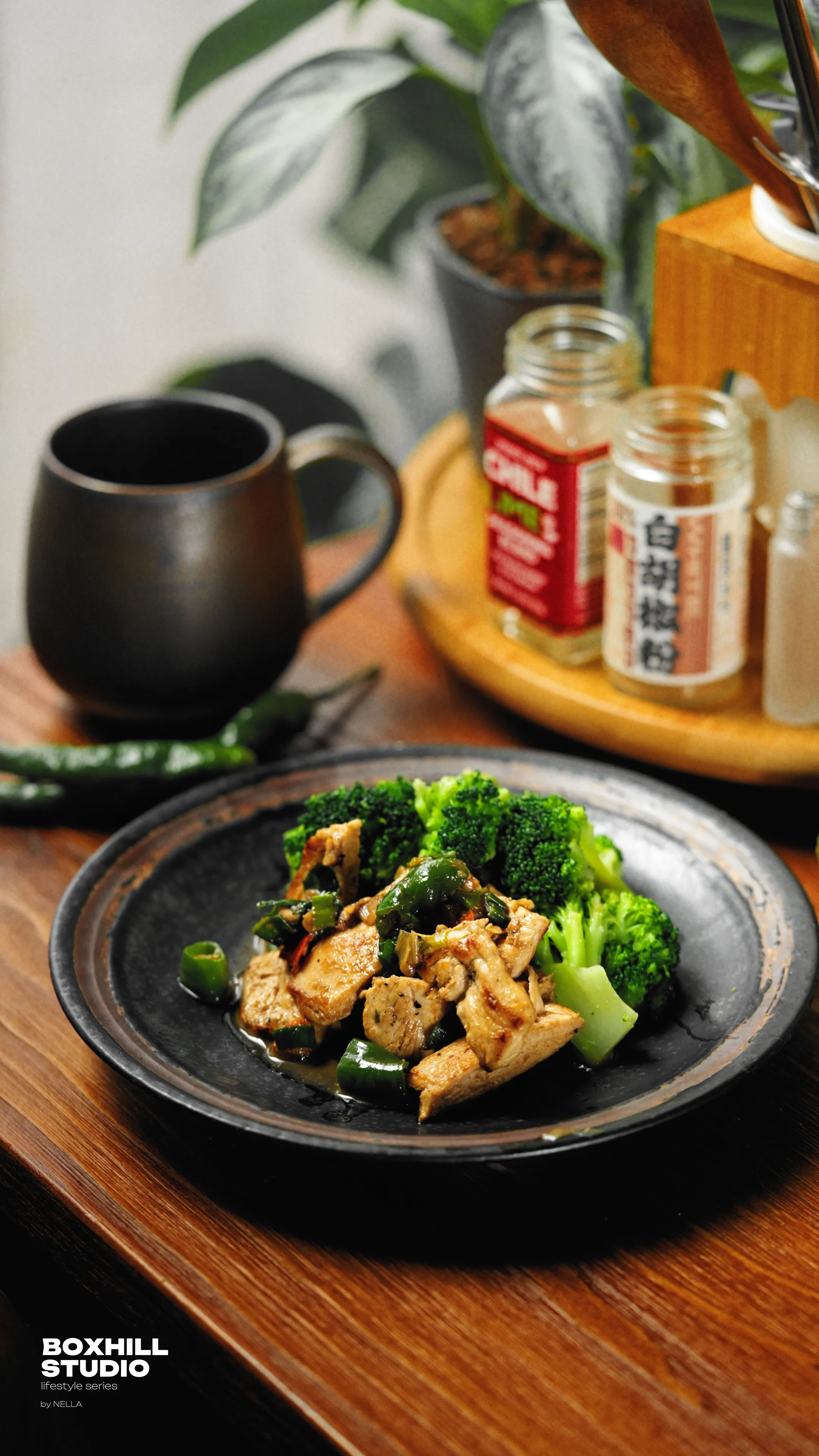 黑色餐盤盛有花椰菜與炒肉片,旁邊放著黑色馬克杯、調味罐與盆栽